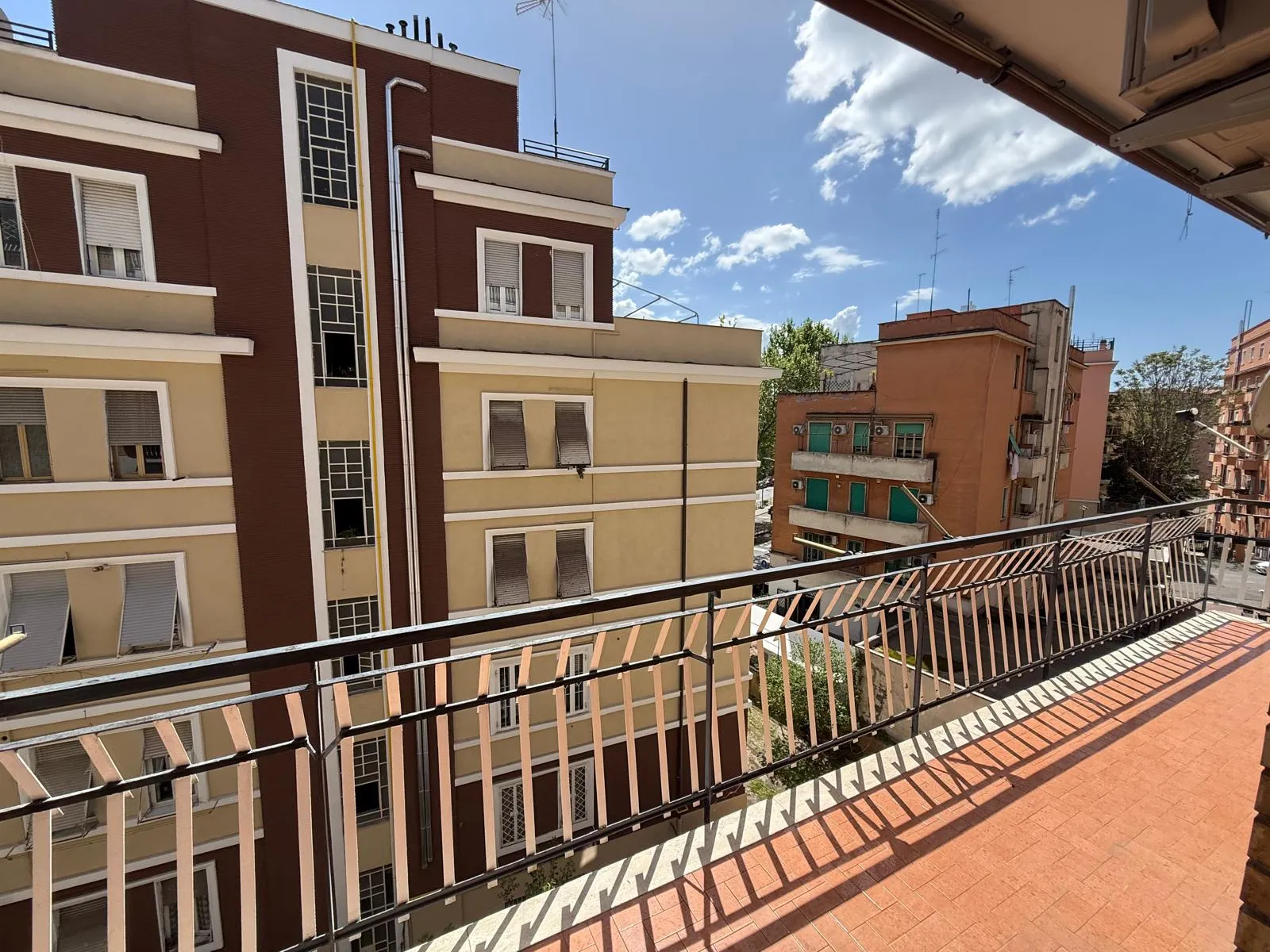 Ampio balcone soleggiato con vista sui palazzi del quartiere